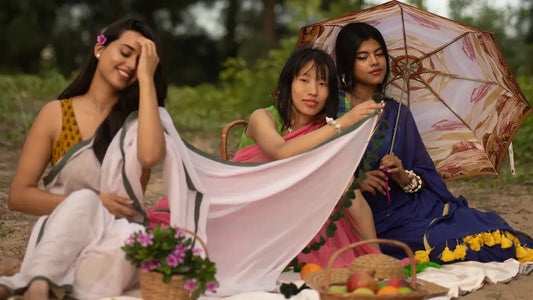 a group of girls wearing saree and resting on the beach