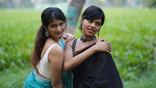 Two girls sitting in a park wearing handloom sarees